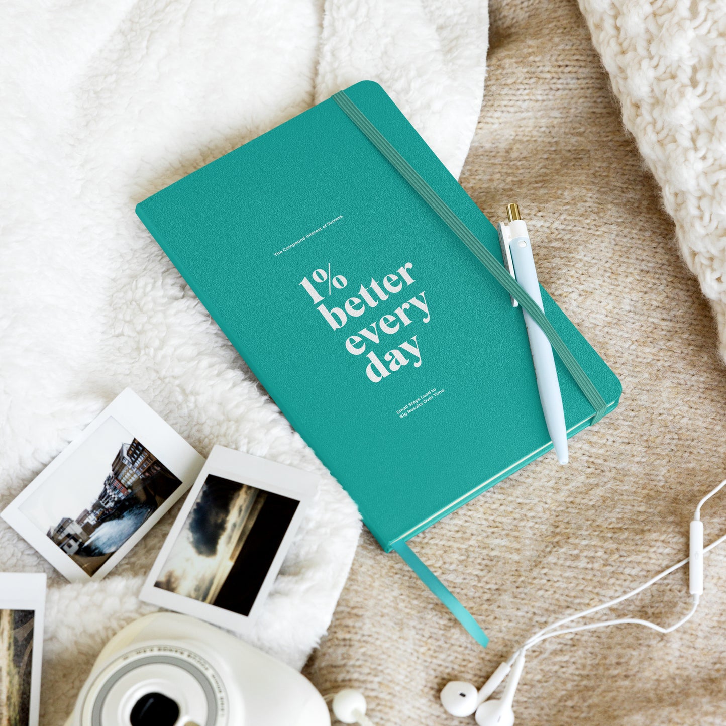 turquoise notebook with '1% better every day' on a marble desk with office supplies. Growth Mindset & Productivity Journal for speakers, leaders, executives, professionals and business owners by wear grit brand
