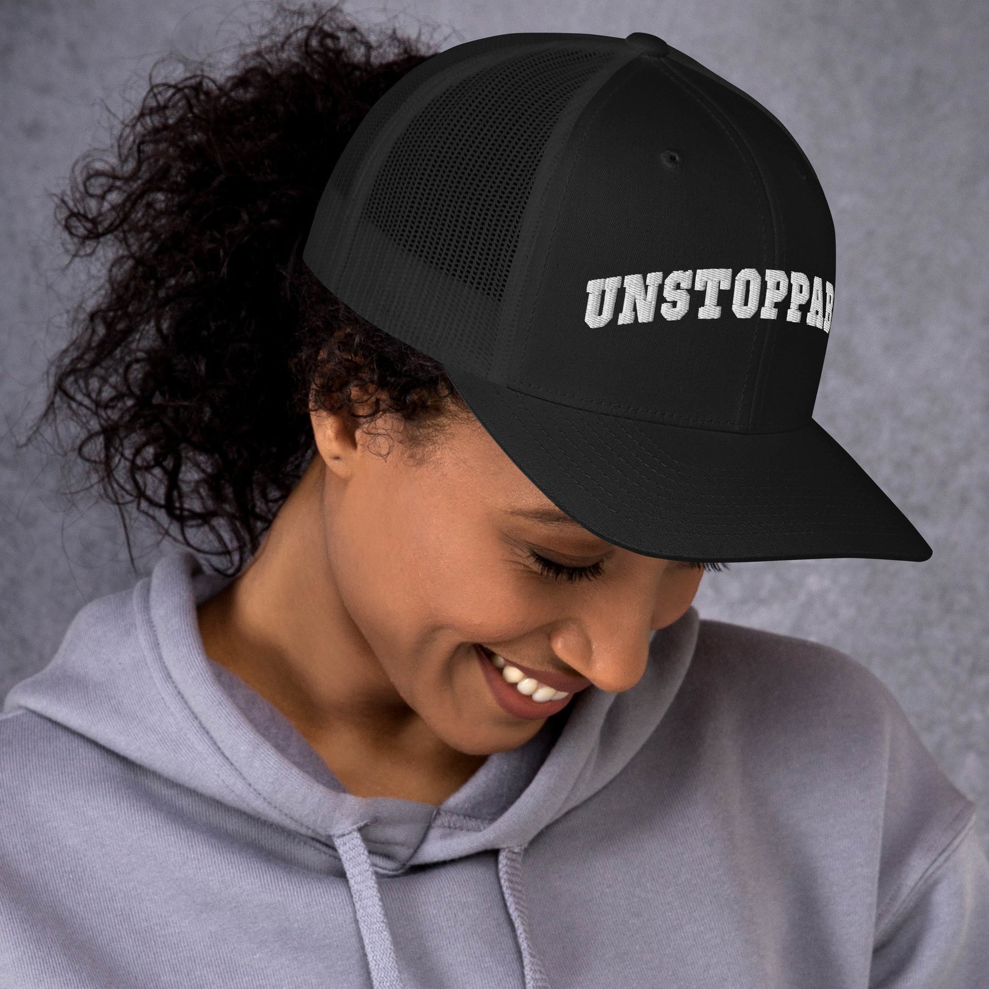 A woman wearing black Unstoppable Trucker Hat mindset-driven by Wear Grit Brand Apparel – structured performance trucker hat for discipline, focus, and consistency
